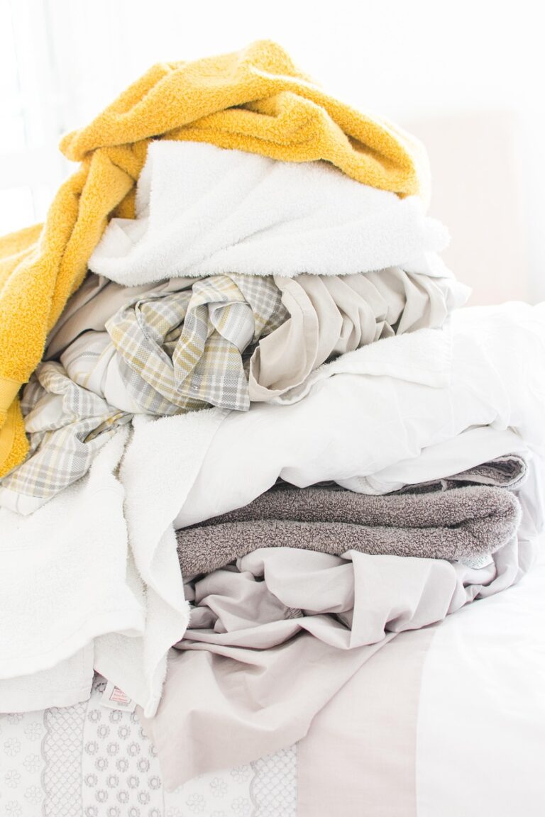A close-up of a woman holding a white laundry basket filled with fresh, clean clothes.
