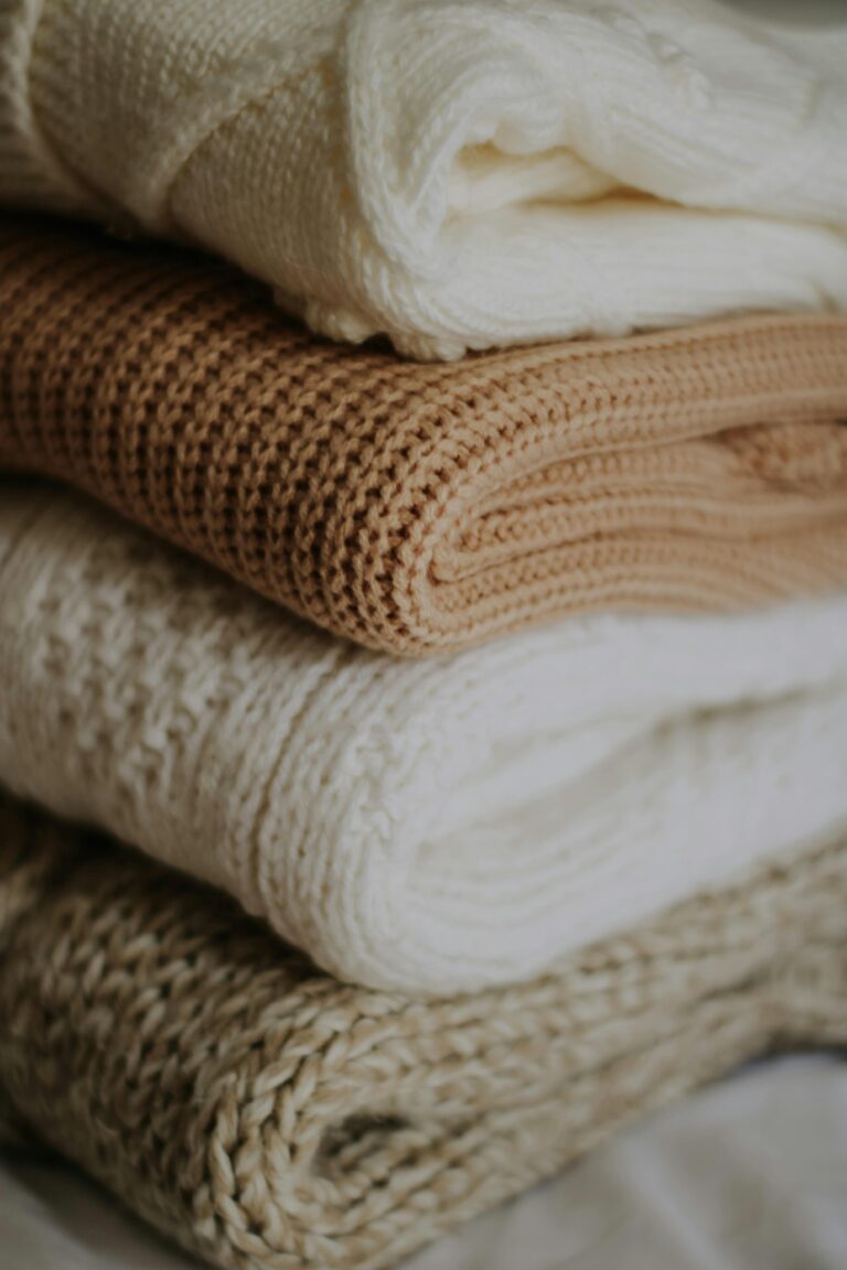 Pile of beige and cream knitted blankets folded neatly for warmth and style.
